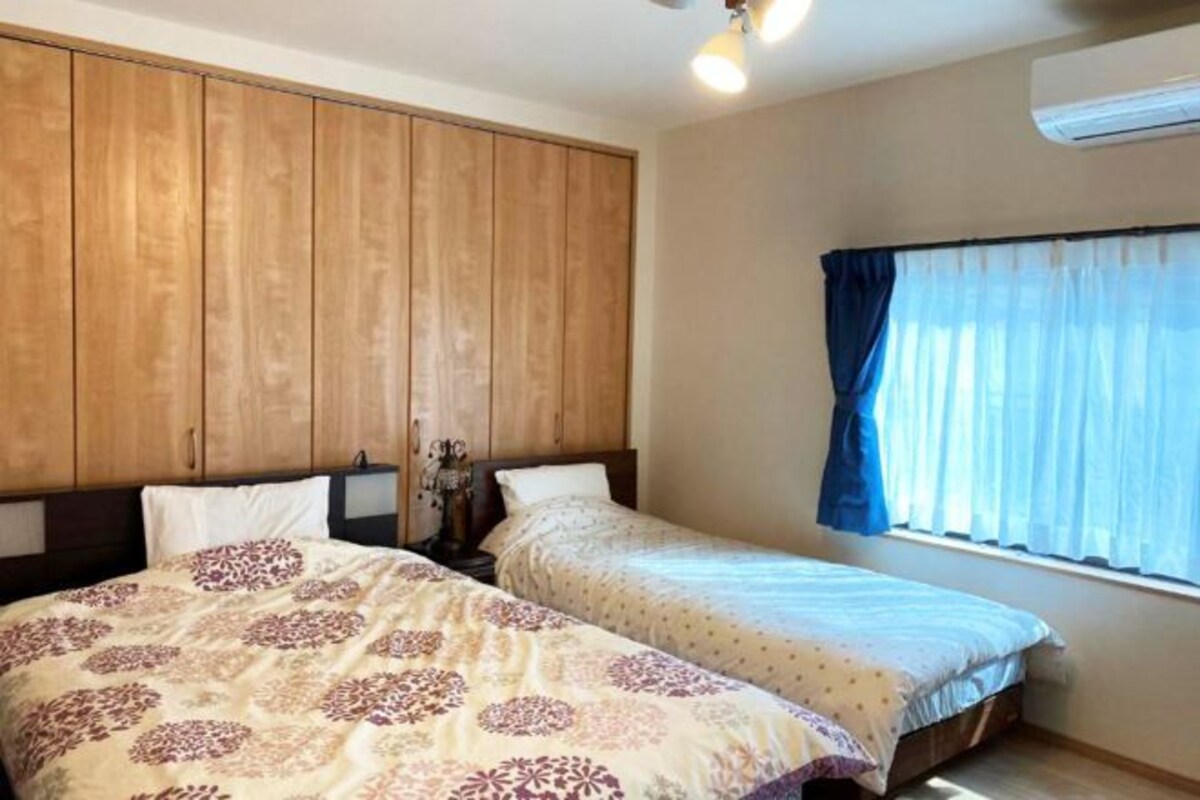 Een slaapkamer met twee bedden, een houten garderobe en een raam met gordijnen.