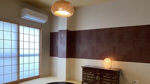 A traditional Japanese room with tatami flooring, a shoji screen, a tatami mat table, a wooden cabinet with a lamp, and a hanging lamp. - Platinum Yasaka (Kyoto)