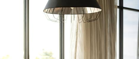 A modern room with large windows, two contemporary chairs, and a hanging lamp.