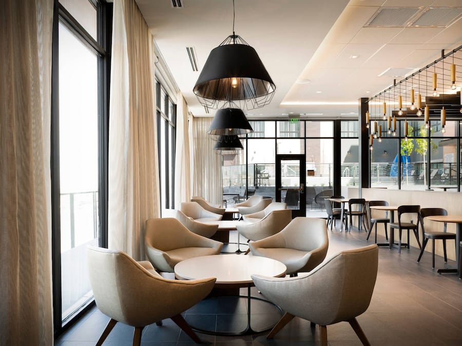 A modern interior with round tables and chairs, large windows, and hanging pendant lights.