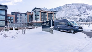 A Courtyard by Marriott hotel with a snow-covered parking area and mountains in the background. - Courtyard by Marriott Salt Lake City Cottonwood (Salt Lake City)