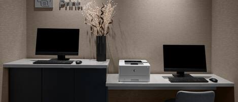 Un escritorio moderno con dos monitores, una impresora y un teclado.