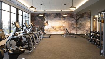 A gym with treadmills, elliptical machines, and weight stations.