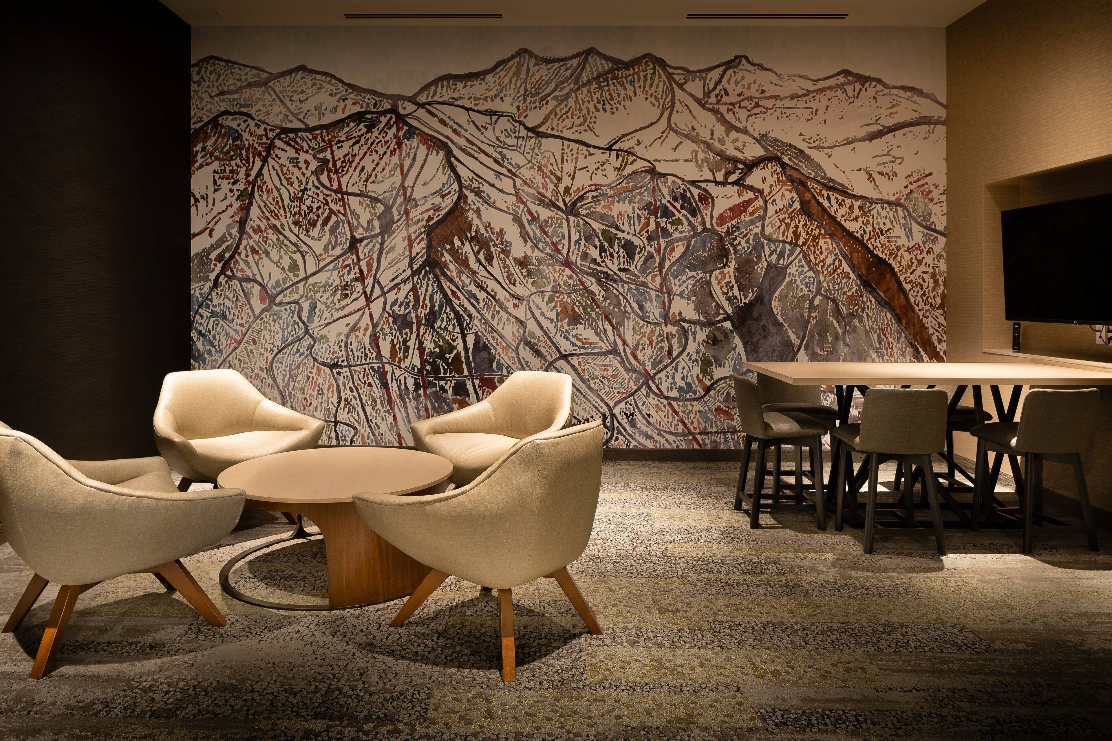 A modern interior with a large abstract mural, a round table, and several chairs.