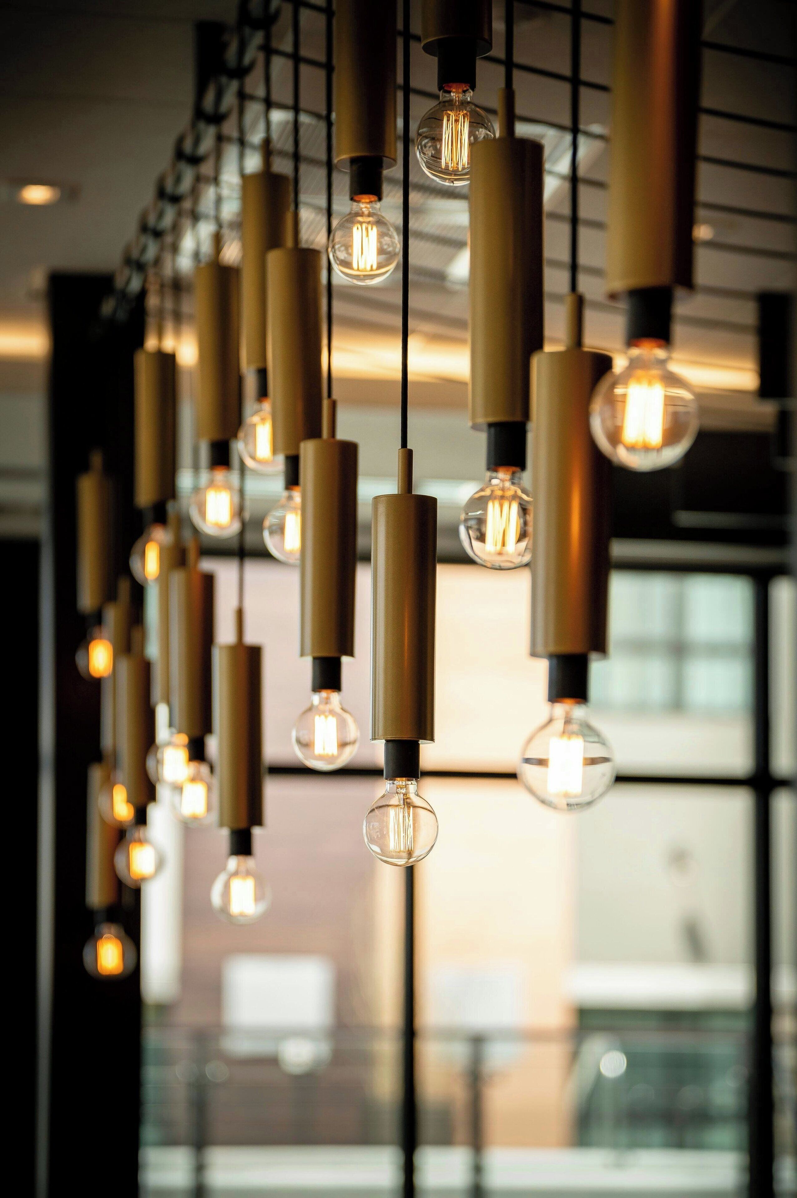 Une série de suspensions modernes, avec des ampoules apparentes, dans un intérieur contemporain.