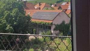 A view from a window with a metal railing, overlooking a residential area with houses and greenery. - Hotel Pension Am Engelsberg (Sommerach)