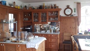 A wooden kitchen with a central island, cabinets, and a dining area. - Hotel Pension Am Engelsberg (Sommerach)