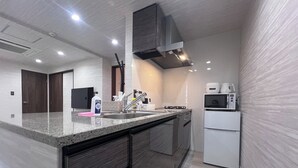 A modern kitchen with a granite countertop, stainless steel sink, and a built-in microwave. - Platinum Kiyomizu (Kyoto)