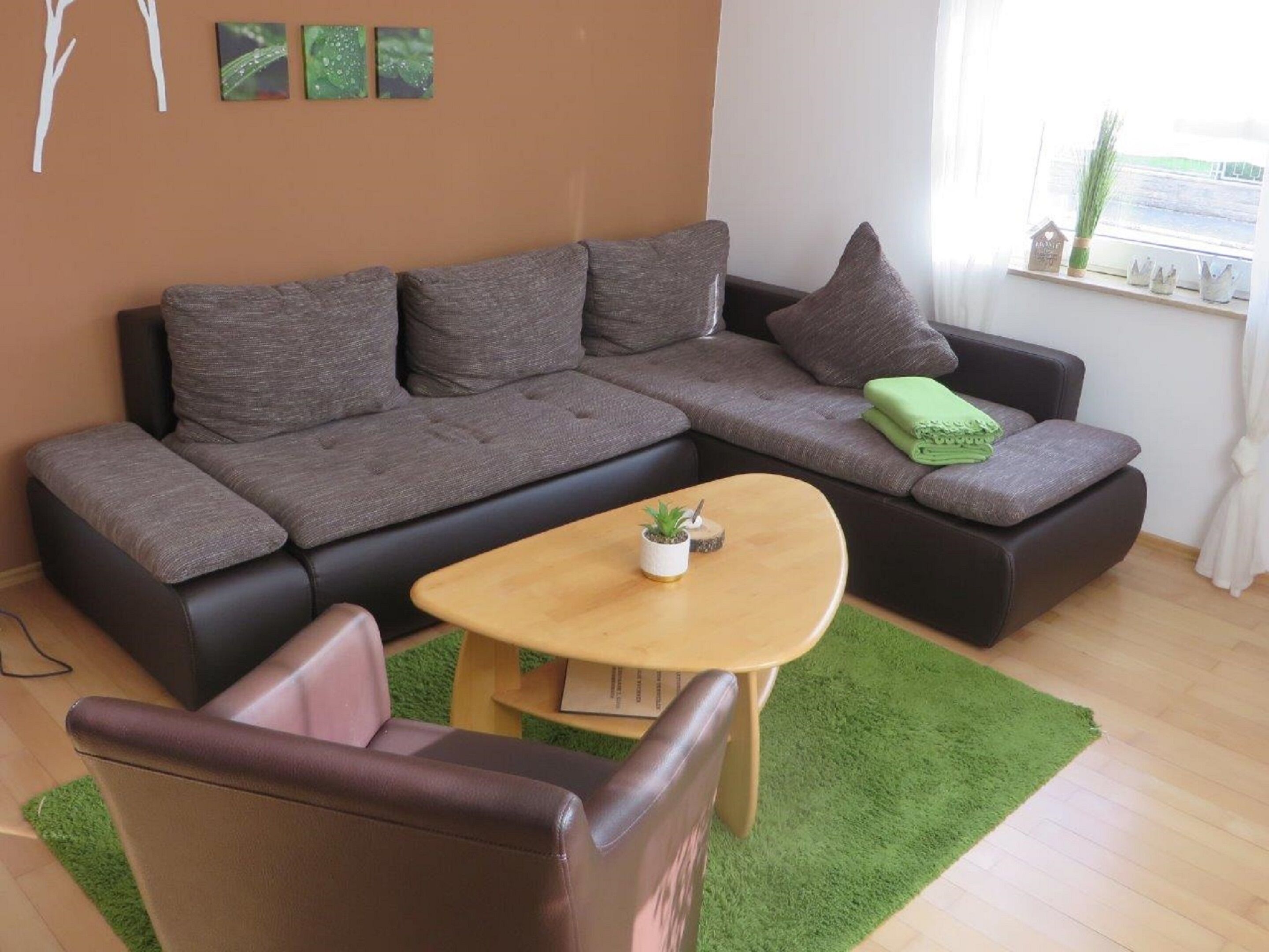 A modern living room with a sectional sofa, a small round table, and a green rug.