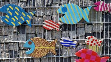 A collection of colorful fish-shaped decorations mounted on a metal fence.