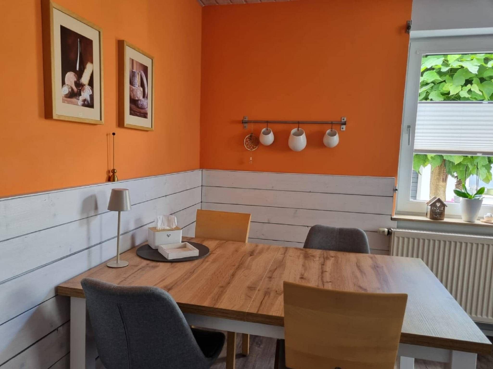 A dining area with a wooden table, four chairs, a small table lamp, and a tissue box.