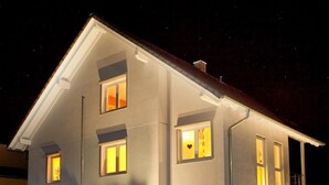 A two-story building with multiple windows, a visible entrance with steps, and a small garden area with potted plants. - Ferienwohnung Familie Buchner (Grossheubach)