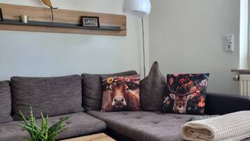 A modern living room with a sectional sofa, a coffee table, a potted plant, and decorative pillows.