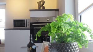 A kitchen with a microwave, oven, and a potted plant on the counter. - Ferienwohnung Familie Buchner (Grossheubach)