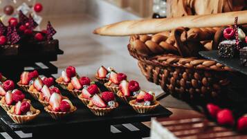 A dessert table with fruit-topped tarts and a basket of bread.