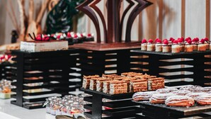 En buffet med et udvalg af desserter og kager, herunder kager og wienerbrød drysset med flormelis.