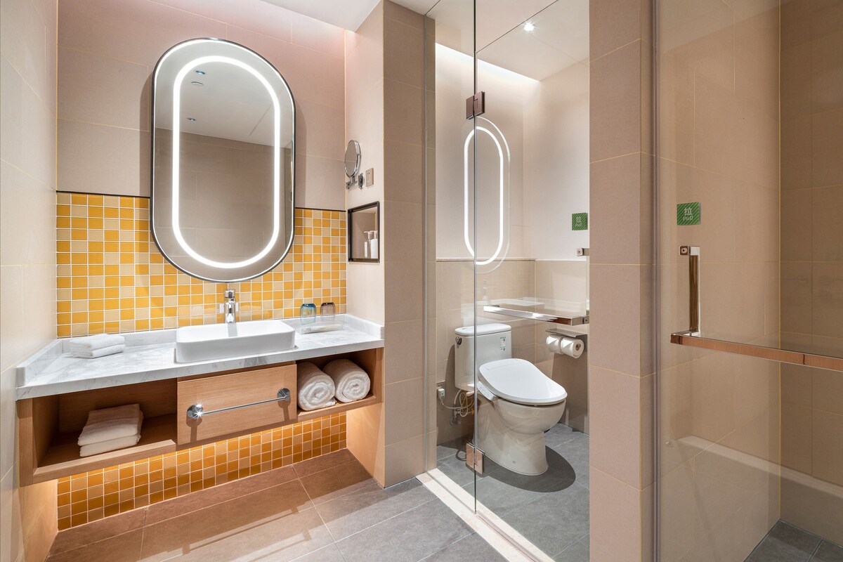 A modern bathroom with a glass-enclosed shower, a sink with a mirror, and a toilet.