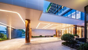 En moderne hotelindgang med en rummelig lobby, høje søjler og en glasfacade.