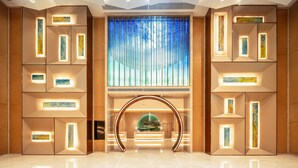 En moderne lobby med en central reception, geometriske vægdesigns og et stort vindue med lodrette persienner.
