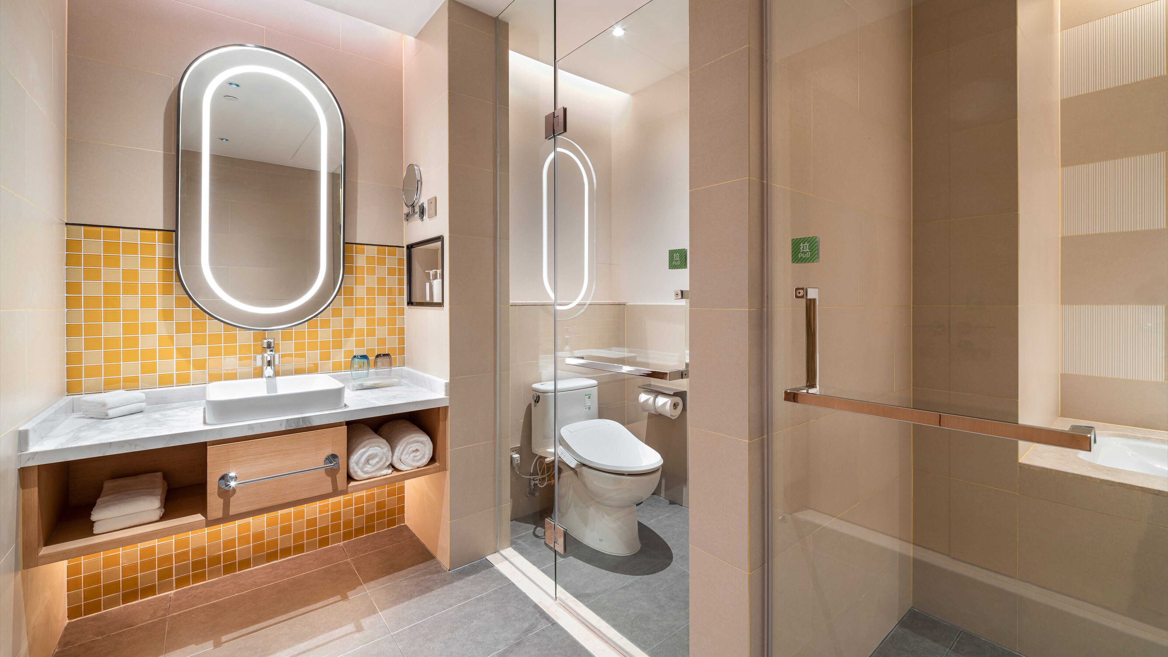 Un baño moderno con ducha de vidrio, lavamanos con espejo e inodoro.