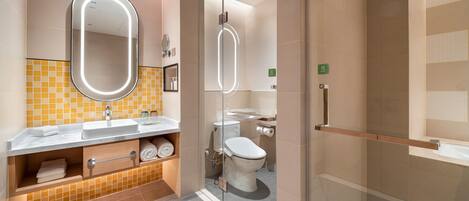 Un baño moderno con ducha de vidrio, lavamanos con espejo e inodoro.