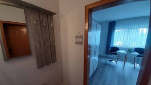 A hotel room with a wooden wardrobe, a small desk, and a dining area with a table and chairs. - Gästehaus Edelmann (Gelnhausen)
