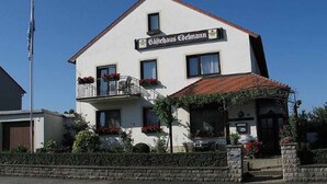 A two-story building with a sign reading "Gasthof Edelmann". It features a balcony with flower boxes and a small porch with a tiled roof. - Gästehaus Edelmann (Gelnhausen)