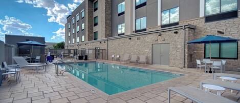Um hotel com piscina, espreguiçadeiras e área de estar ao ar livre.