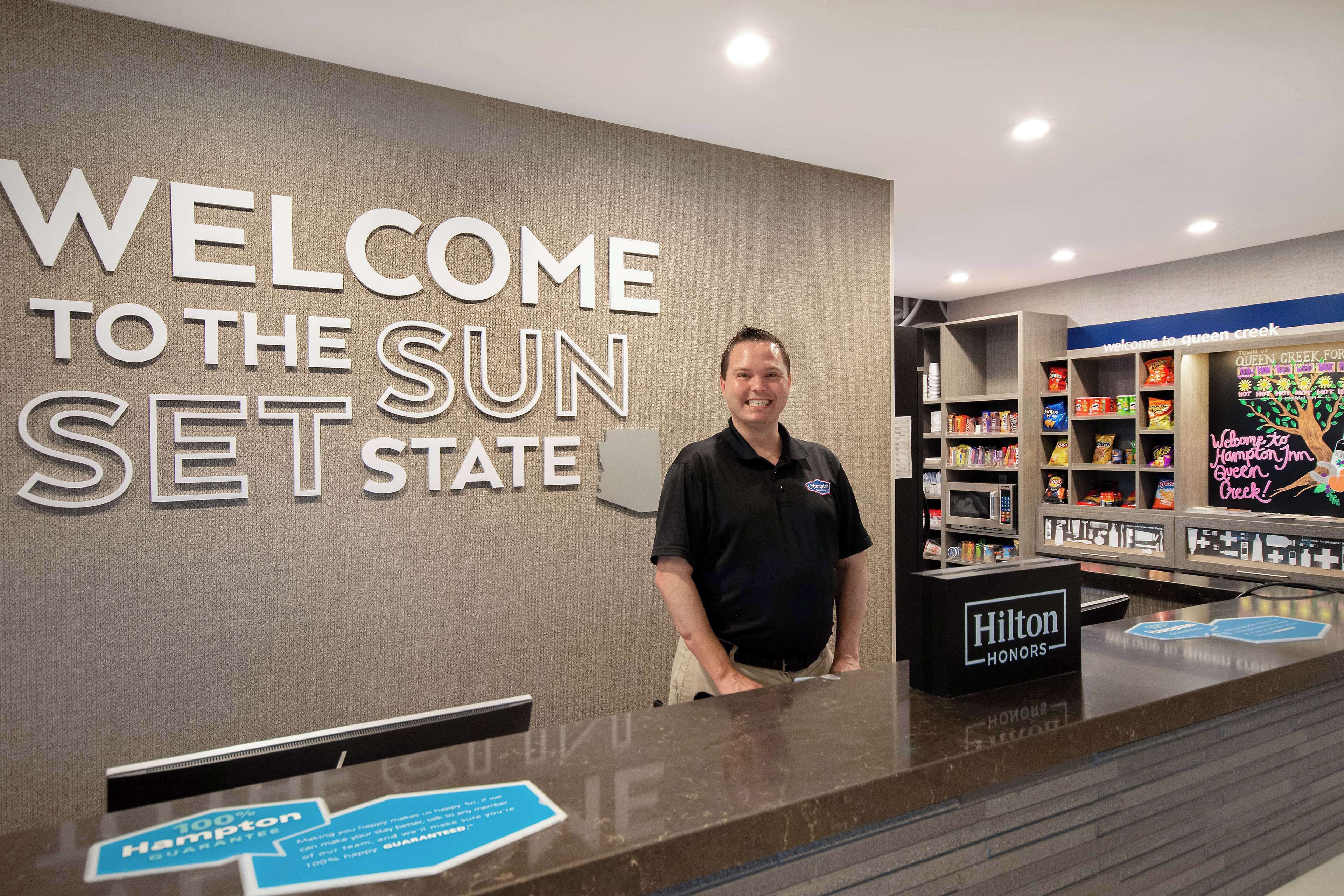 A reception desk with a sign reading "WELCOME TO THE SUN SET STATE" and a "Hilton Honors" sign.
