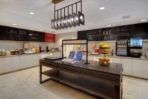 A breakfast area with a counter, food display, and a sign that reads "HAPPY BREAKFAST STARTS HERE". - Hampton Inn Queen Creek (Queen Creek)