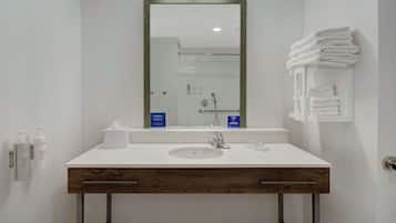 Un bany modern amb un lavabo blanc, un moble de tocador de fusta i un mirall.