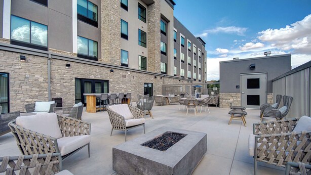 A courtyard with outdoor seating, a fire pit, and a building with multiple windows and a stone facade.
