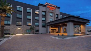 A modern Hampton Inn hotel with a welcoming entrance, a stone facade, and a well-lit exterior.