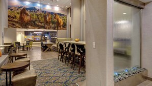 A hotel lobby with a bar area, seating arrangements, and a large mural of horses.