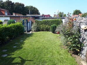 A well-maintained backyard with a lawn, a wooden fence, and various plants. - Steinhagen A. Timmendorf Beach - Vacation Home in Timmendorf Beach (Insel Poel)