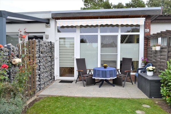 A patio with a table and chairs, a small garden, and a building with a number 53 sign. - Steinhagen A. Timmendorf Beach - Vacation Home in Timmendorf Beach (Insel Poel)