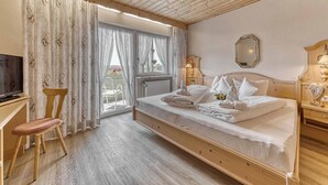 Ein Schlafzimmer mit einem hölzernen Bett, einem Fernseher, einem Sessel und einem Fenster mit Vorhängen.