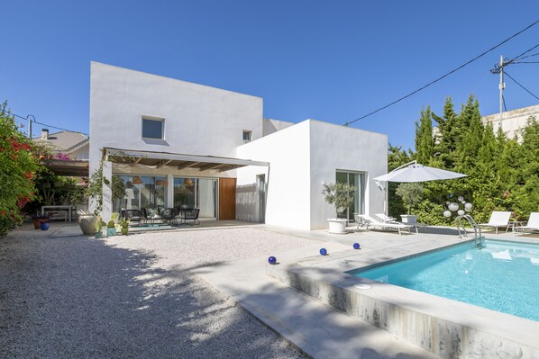 Une maison moderne dotée d’une piscine, d’un espace salon extérieur et d’un patio couvert.