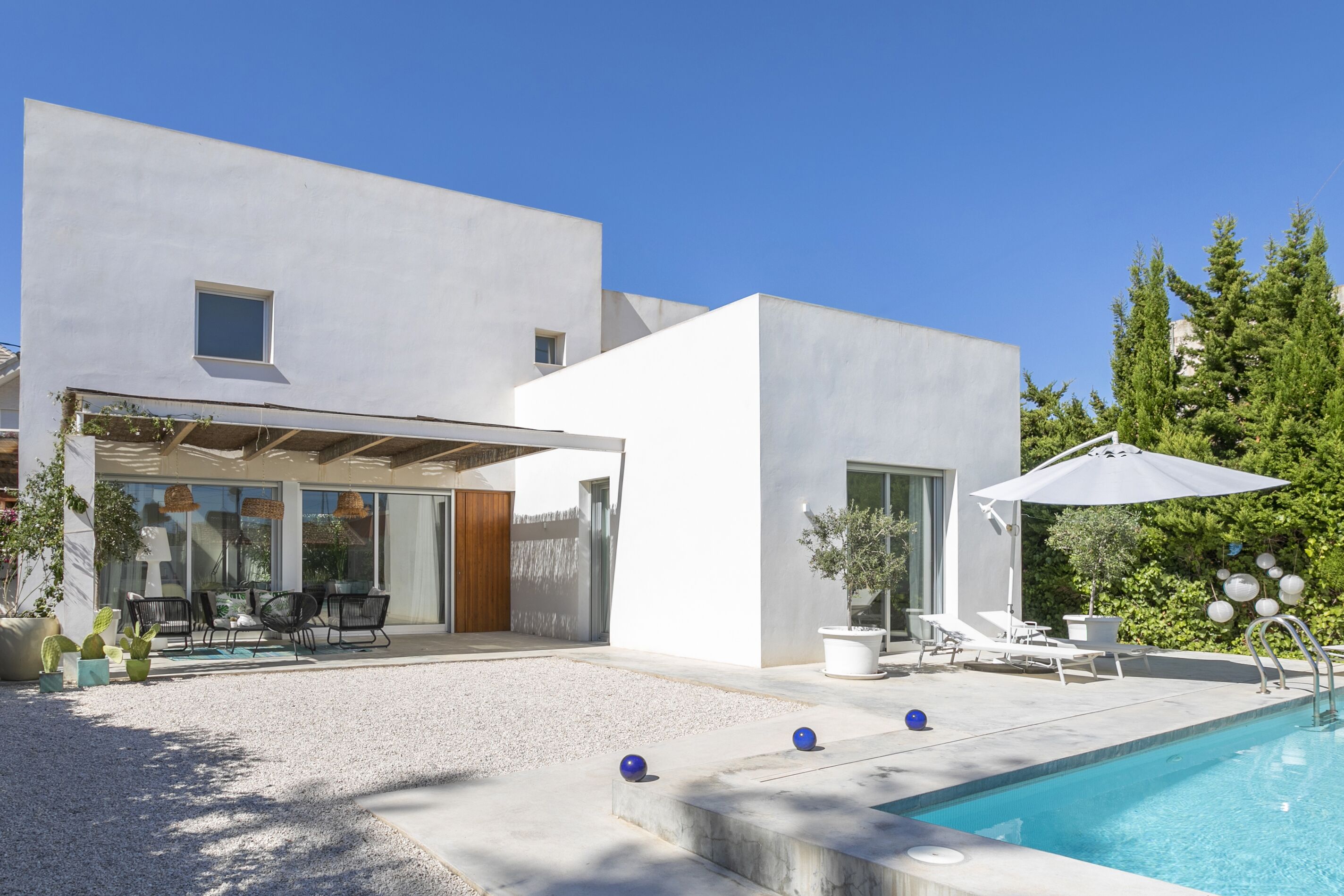 Een modern huis met een zwembad, buitenzitplaatsen en een overdekt terras.