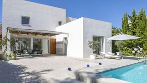 A modern house with a pool, outdoor seating, and a covered patio area.