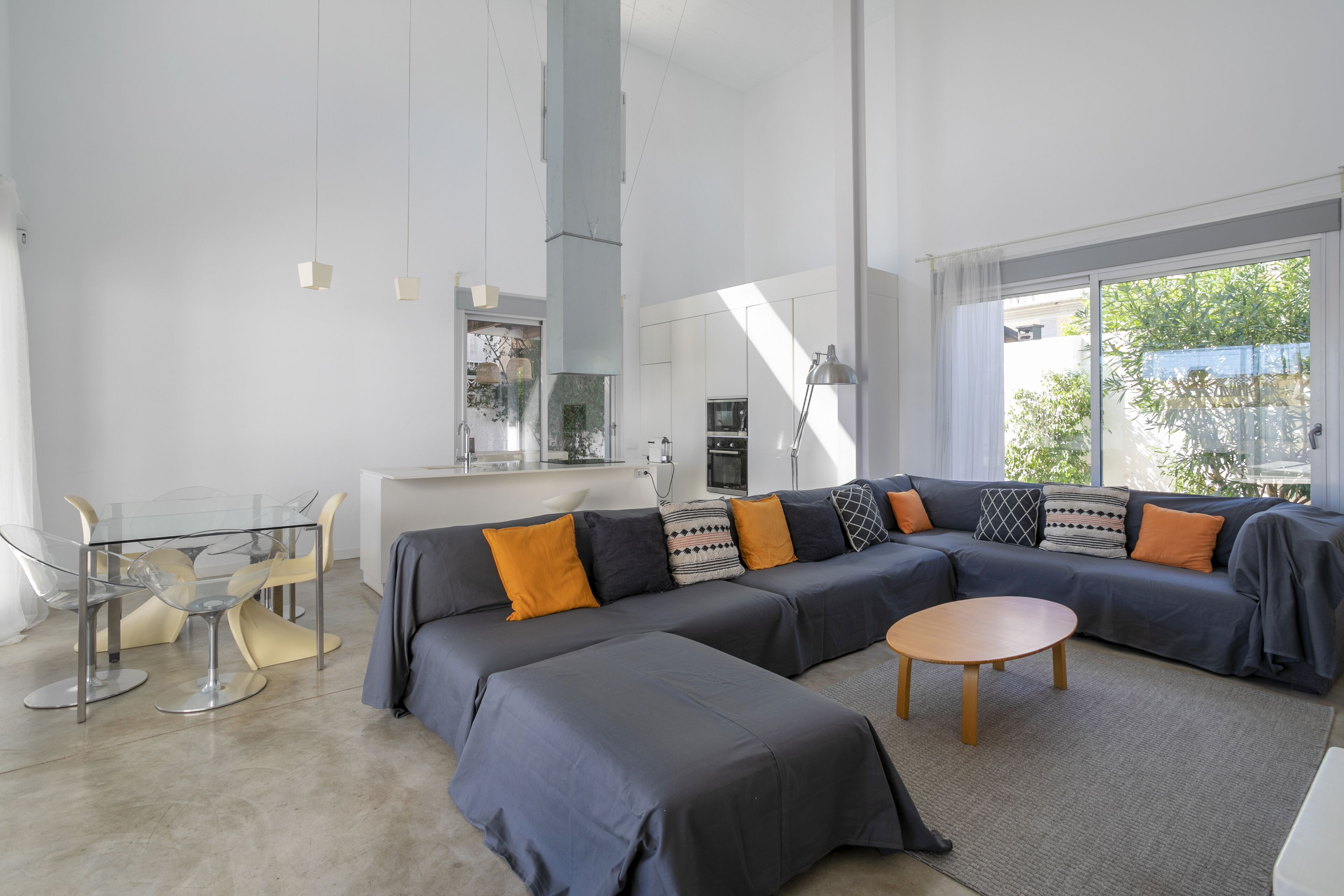 Een moderne woonkamer met een hoekbank, een glazen eettafel en een keuken op de achtergrond.