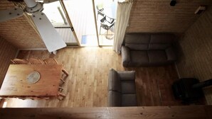 Una habitación con piso de madera, una mesa de comedor con sillas, un sofá y un ventilador de techo.