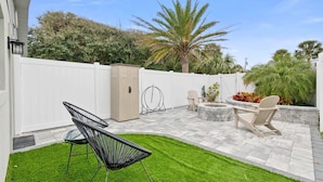 A patio area with a white fence, a small garden, and outdoor furniture.