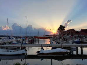 Ein Yachthafen mit vor Anker liegenden Booten, einer Holzsteganlage und Gebäuden im Hintergrund.
