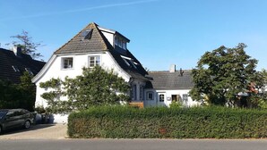 Ein zweistöckiges Haus mit einem steilen Satteldach, Dachgauben und einem sichtbaren Schornstein.