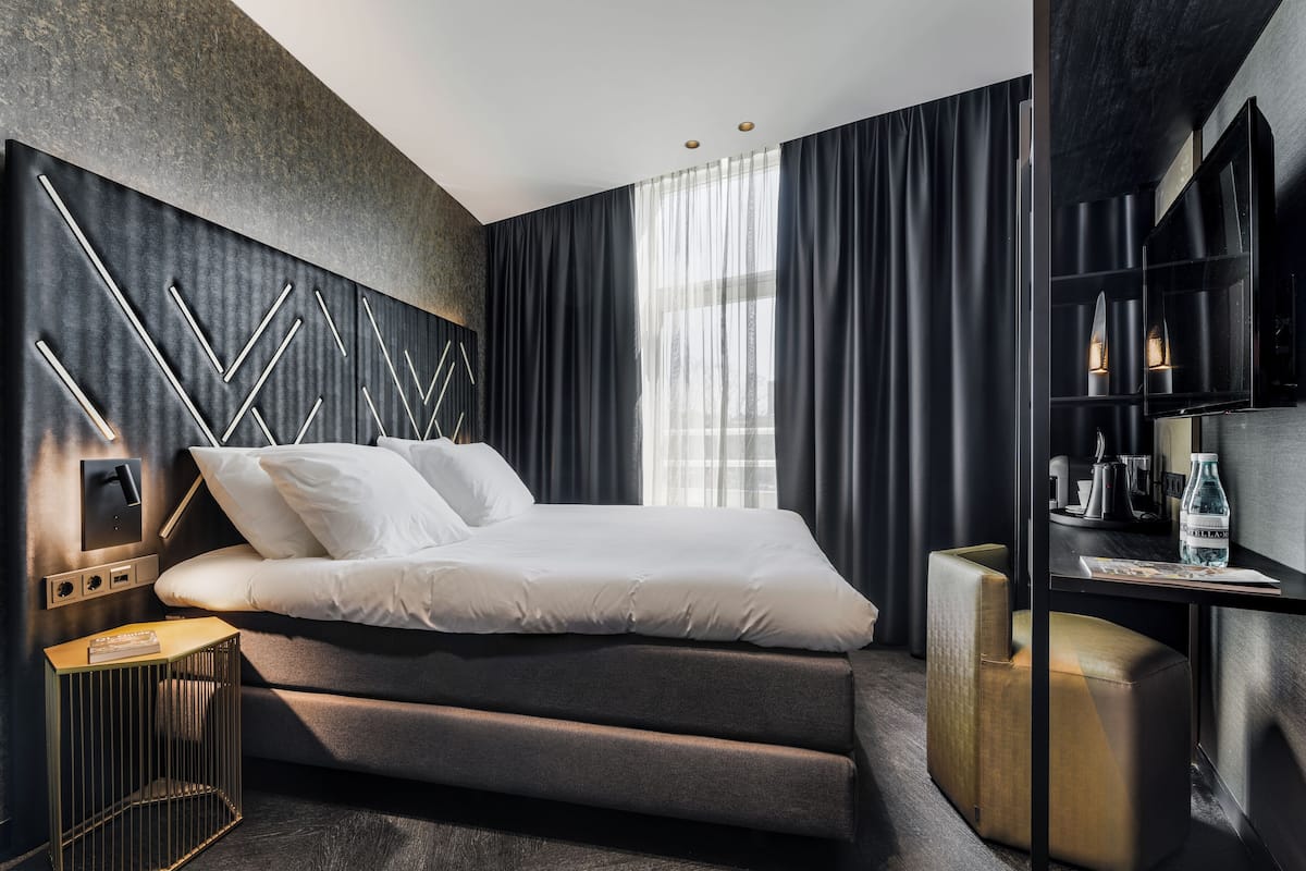 Ein modernes Schlafzimmer mit einem Bett, Nachttischen und einer integrierten TV-Konsole.