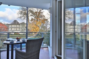Un balcón con una mesa, sillas y vistas a edificios y árboles.