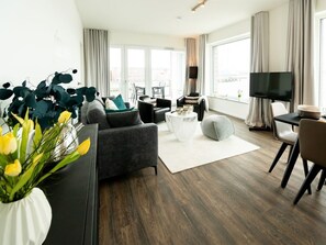 A modern living room with a sofa, armchairs, a coffee table, and a TV. - Hafenspitze App. 16 Pier 2.16 (Wismar)