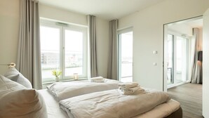 A hotel room with two beds, a large window, and a view of the city. - Hafenspitze App. 16 Pier 2.16 (Wismar)