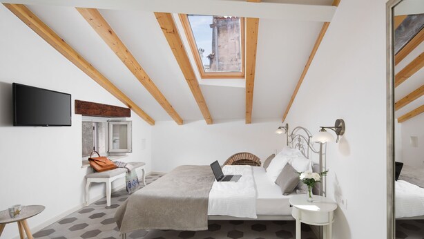 Une chambre avec un puits de lumière, un lit, un bureau et une télévision.